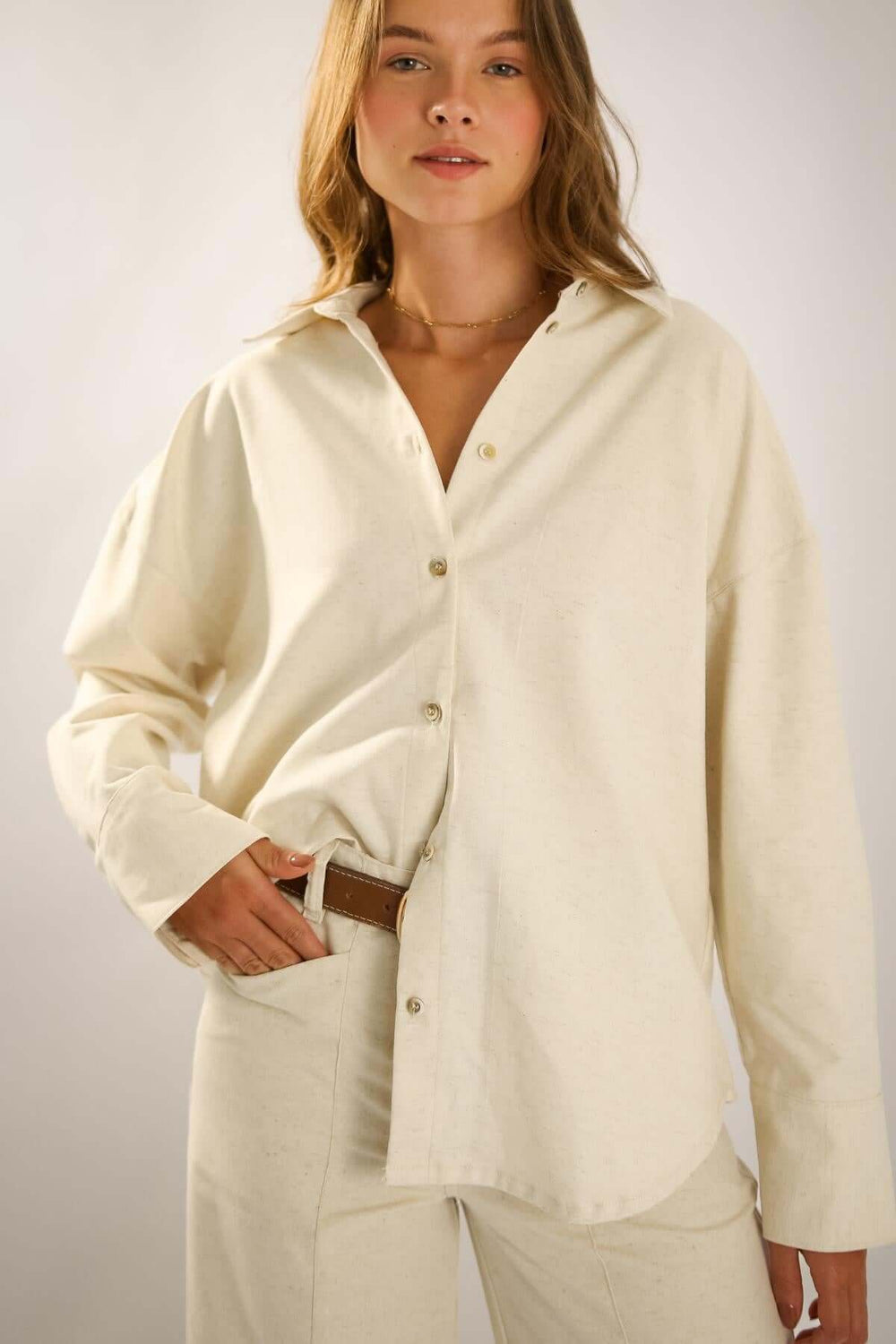 Camisa Ovesized Algodão Linho em tom bege, modelagem ampla, com detalhes modernos e sofisticados.