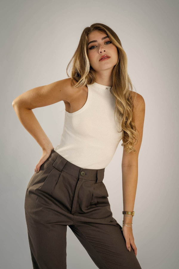 Modelo usando calça alfaiataria algodão cinza e blusa branca, posando em fundo neutro.