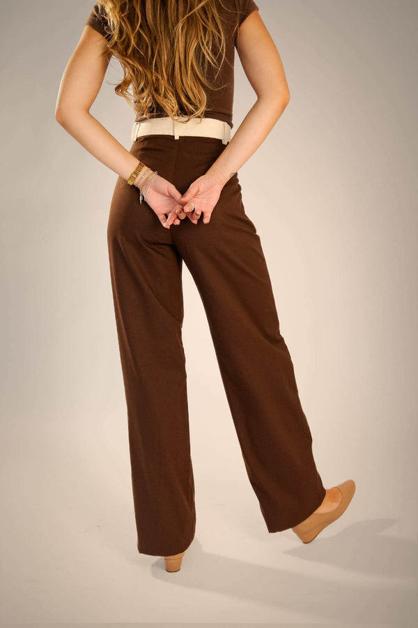 Mulher usando calça alfaiataria marrom com recorte no bolso diagonal, vista traseira.