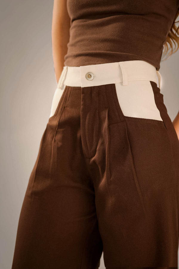 Calça alfaiataria marrom com recorte no bolso diagonal, confeccionada em tecido 100% algodão.