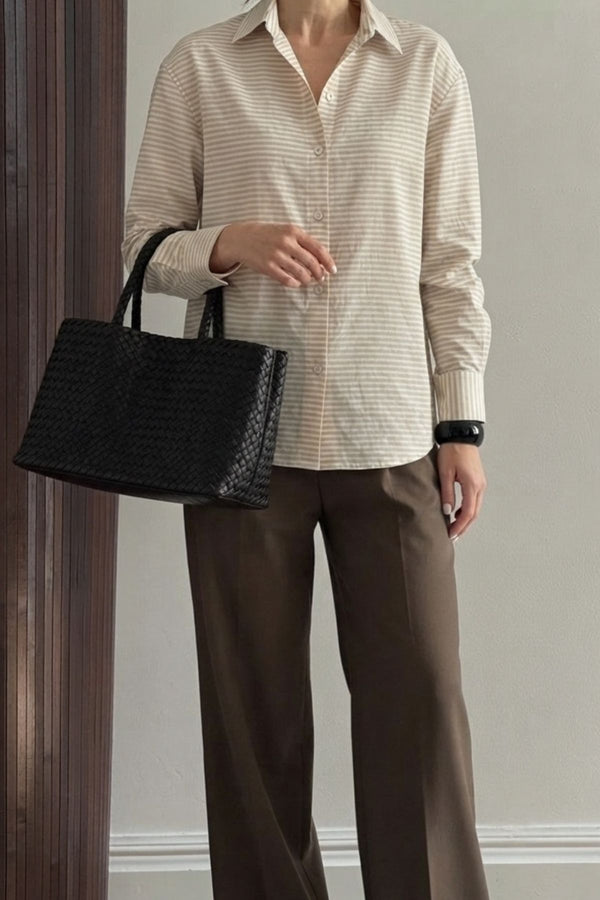Camisa oversized algodão listrada bege combinada com calças marrons e bolsa preta, estilo chique e confortável.