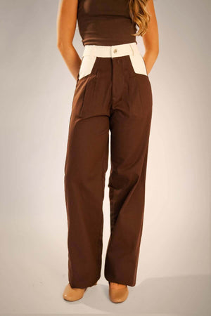 Calça alfaiataria marrom com recorte no bolso diagonal, modelo reto, confeccionada em 100% algodão, display de look elegante.